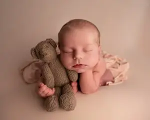 newborn baby girl holding teddy